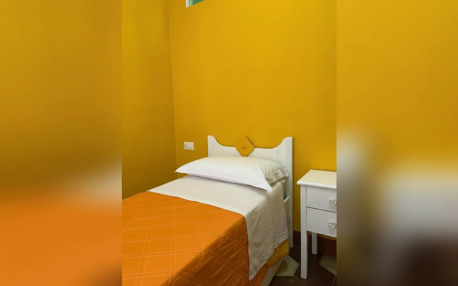 Il letto singolo della Camera Arancia del Vesuvio con il comodino