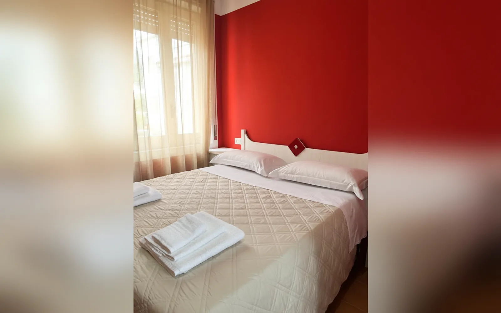 Il letto matrimoniale con gli asciugamani e la finestra con le tende